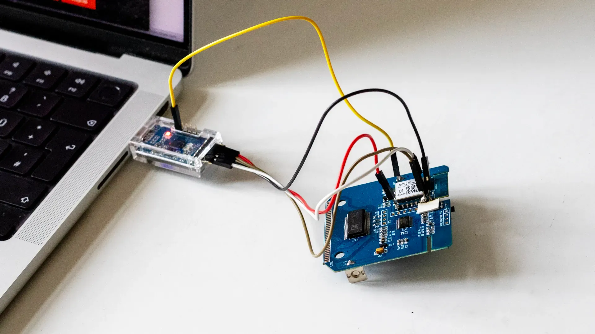 A PCB connected to a MacBook via a USB to TTL UART converter